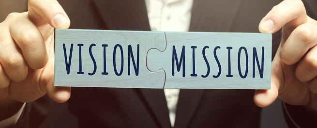 istockphoto-1295825535-170667a Businessman connects wooden puzzles with the words Vision Mission. Concept for business ideas and goals. Strategy development. Planning and action plan. Performance, motivation and company management.